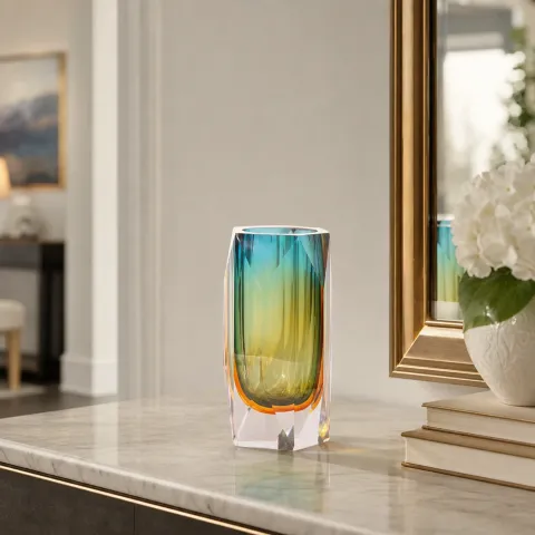 Glass vase on a marble console beside a gilded mirror and white hydrangeas
